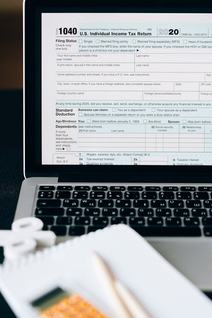 who-we-are Close-up of a tax form on a laptop screen with a calculator and notebook in the foreground.